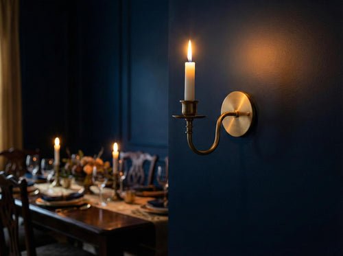Dining room with a candlelit table and wall-mounted candle holder against a dark blue wall.