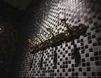 Gold coat rack on a black and white tiled wall
