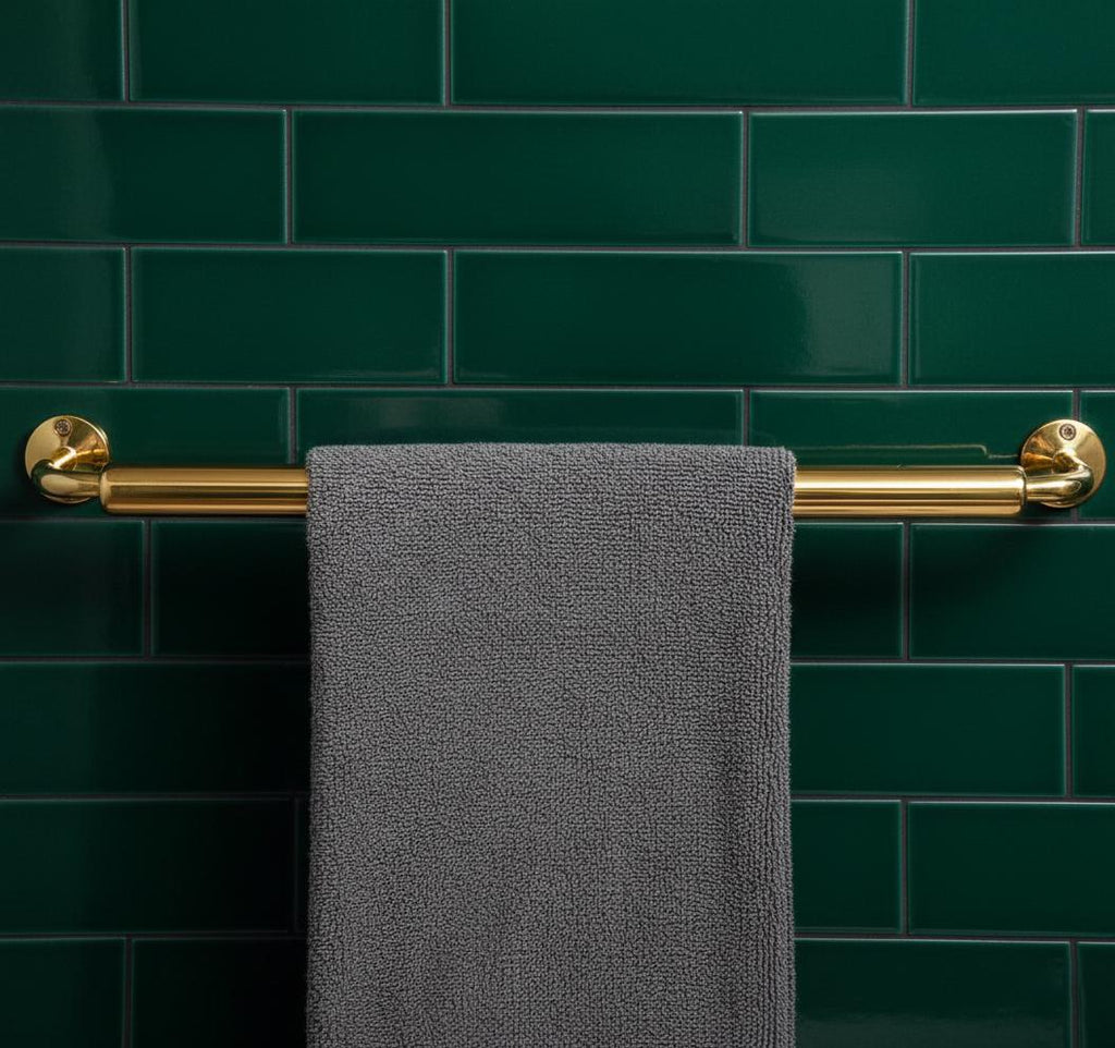 Gray towel hanging on a gold towel rack against a green tiled wall