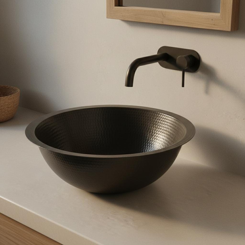 Black hammered sink on a bathroom counter with a wall-mounted faucet.