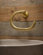 Gold towel hook on a wooden wall above a sink