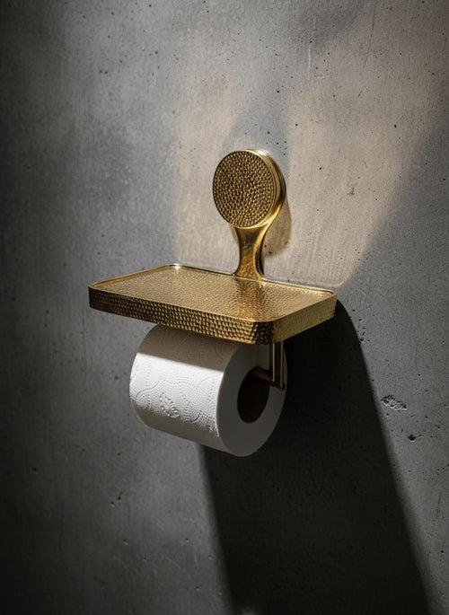 Gold toilet paper holder with textured design on a concrete wall.