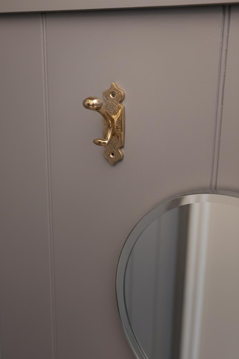 Close-up of a gray cabinet with a gold handle and round mirror.
