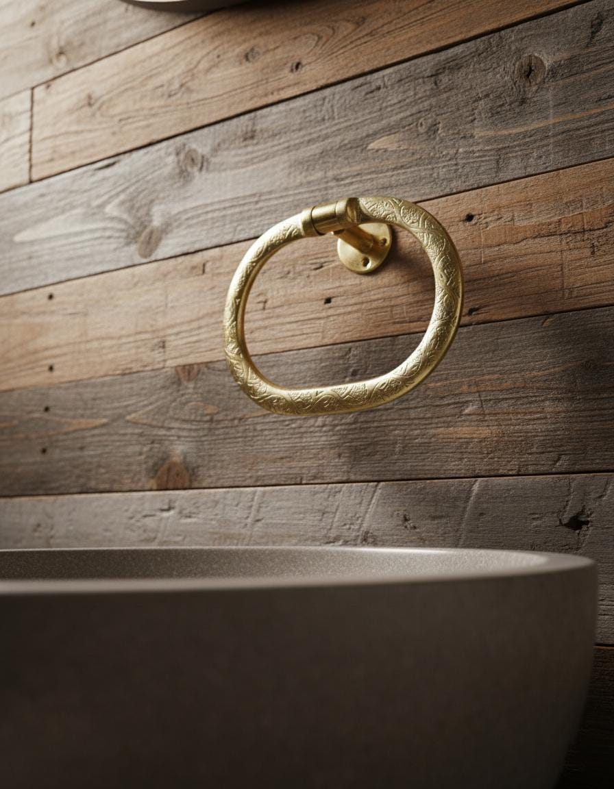 Gold towel ring on a wooden wall with a concrete sink below