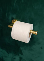 Roll of toilet paper on a gold holder against a dark green background