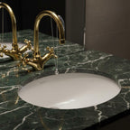 Gold faucet and white sink on a green marble countertop