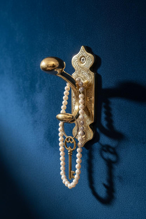 Decorative gold hook with pearls and a key on a blue background