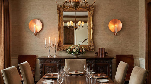 Elegant dining room with a mirror, candles, and flowers on a table.