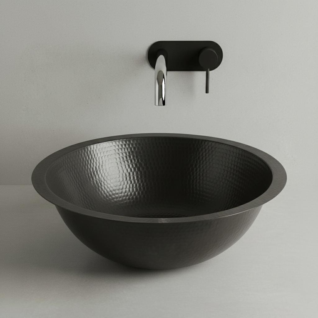 Black hammered sink with a wall-mounted faucet on a light gray background