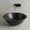Black hammered sink with a wall-mounted faucet on a light gray background